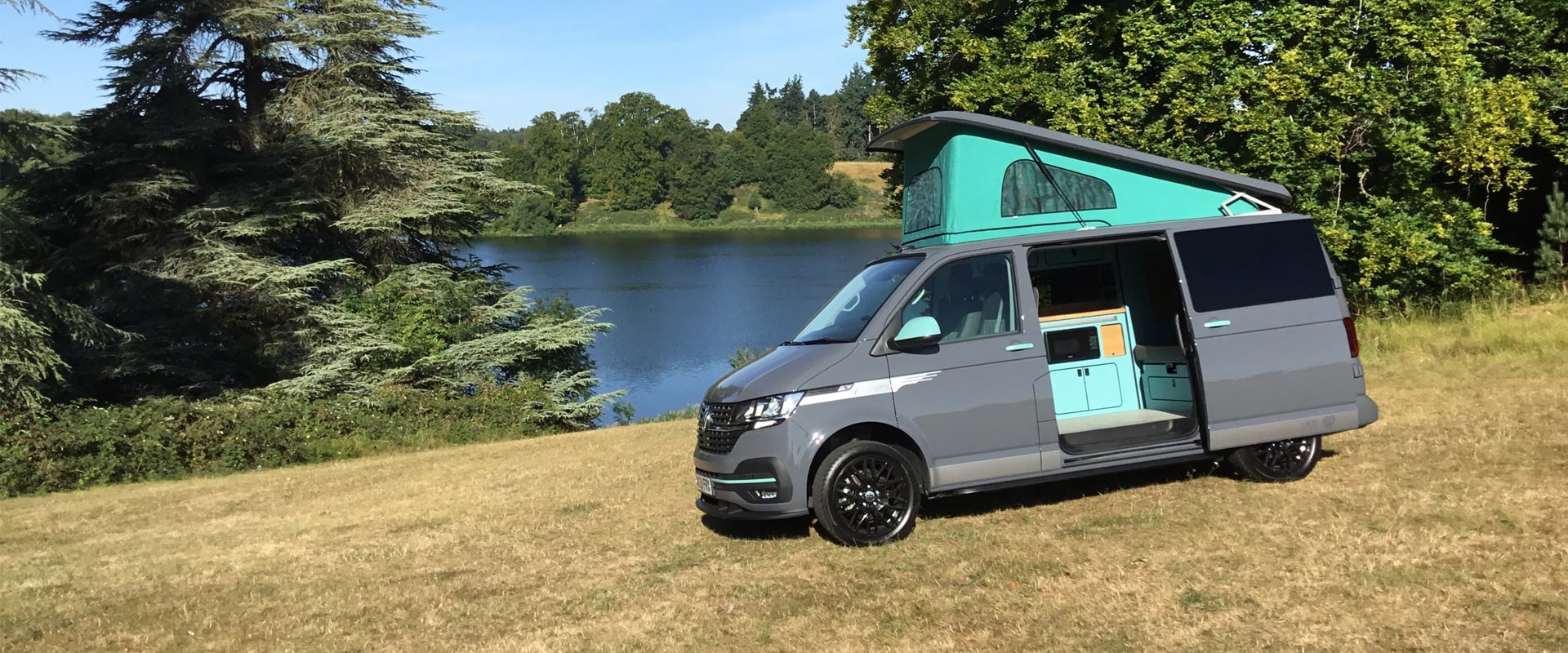 VW Transporter Hand Built Cotswold + Campervan parked beside a lake in Oxfordshire